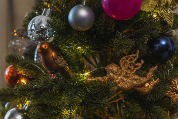 Birds, angels and other Christmas tree toys on a sparkling tree. Festive background for New Year or Christmas.
