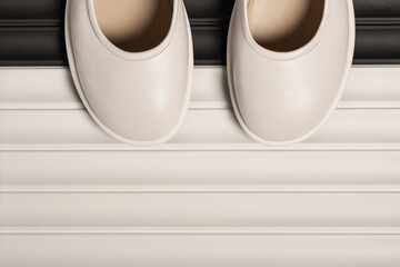 A pair of white shoes on a decorative relief panel with copy space.