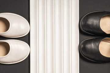 Two pairs of white and black shoes separated by a decorative relief panel with a copy of the space.