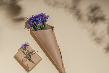Cornflower bouquet and gift box in craft paper. Greeting card mockup.