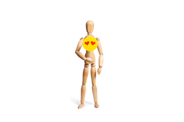 A wooden toy mannequin holding a round yellow sign wit two red hearts on white background