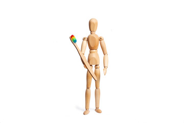 A wooden toy mannequin holding a toothbrush in his hand on white background
