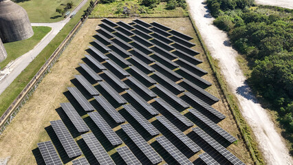 Imagem aérea de painéis solares instalados em solo industrial, destacando geração de energia...