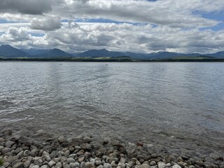 lake and clouds Calm lake with gentle ripples reflecting cloudy sky and distant mountains, tranquil natural landscape. 