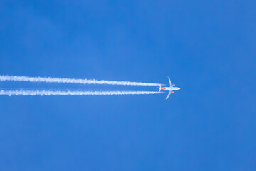 Airplane in the blue sky creating contrails