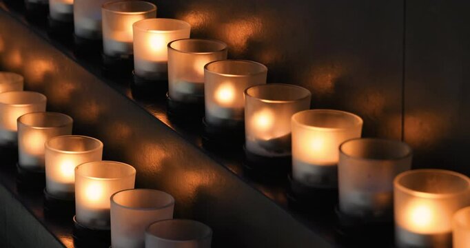 Memorial candles flicker in dark room religion. Remember and sorrow for those who have passed and died before. Religion and faith in church and cathedral. 4K HD video footage.