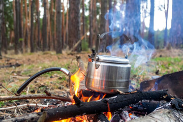 Boiling water with a stainless steel kettle in the forest