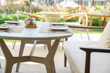 white dish with stainless steel spoon, knife, and fork on plate mat setting on the restaurant outdoor table.