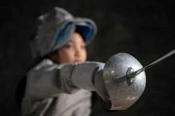 A girl in fencing gear sitting on a bench, ready for the épée competition