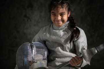 A girl in fencing gear sitting on a bench, ready for the épée competition