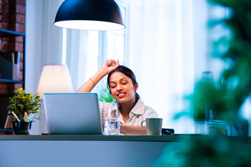 Indian businesswoman feels pressure and headache while working on laptop at modern office desk