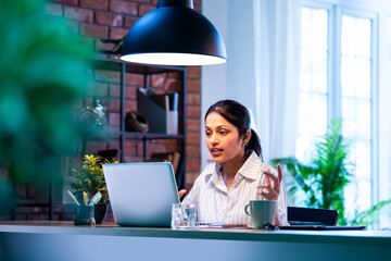 Indian executive uses laptop and headphone for remote video call at home or office workspace