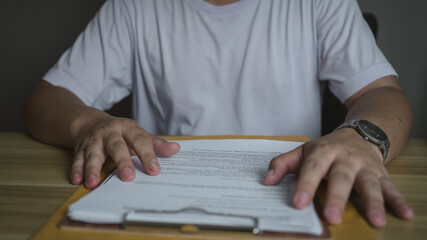Man placing hands on a document at a wooden desk. Business, decision-making, or legal review...