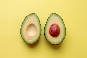 Avocado cut in half  on a yellow background