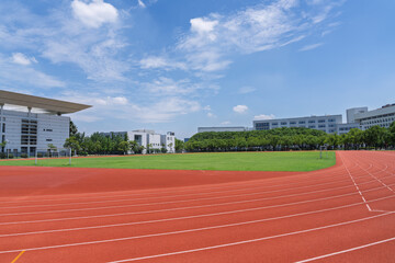 University campus football field and running track under blue sky and white clouds