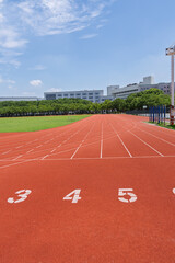 University campus football field and running track under blue sky and white clouds