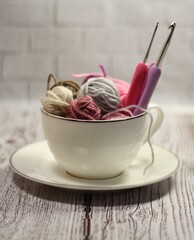 A cup and a saucer with clews balls of yarn wool and crocheted blanket handmade craft bright photo	
