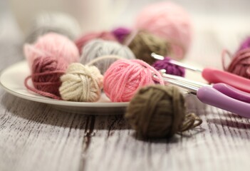 Clews of yarn wool balls on the plate and crochet hooks photo 