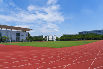 University campus football field and running track under blue sky and white clouds