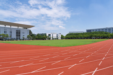 University campus football field and running track under blue sky and white clouds