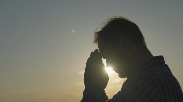 man praying at sunset, asking heaven for help and support, spiritual man contemplating, the concept of faith and hope, reflections in the rays of sunlight, trustworthy religion.
