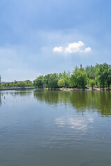 Fototapeta premium The reflection of the city oasis in the lake under the blue sky and white clouds