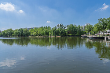 The reflection of the city oasis in the lake under the blue sky and white clouds