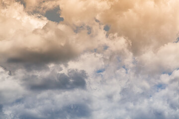 White textured clouds with rays of sunlight close-up, a heavenly landscape with clouds in the sky, clouds with warm sunlight peeking through.