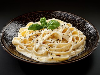 A plate of freshly made pasta--creamy fettuccine Alfredo with parmesan shavings and cracked black pepper