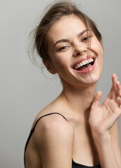 Cheerful young woman with long hair smiling and expressing joy, dressed in a simple black top, on a...