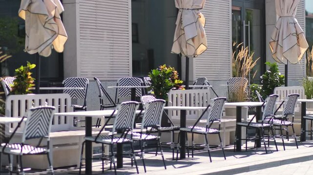 Sidewalk cafe with small round tables and empty chairs - coffeehouse, coffee shop, diner or restaurant.