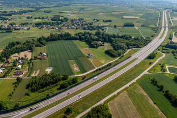 Aerial view of modern highway running through rural countryside with green fields and scattered villages during summer, transportation planning