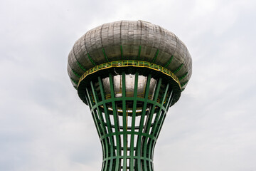 Close-up of unusual green and grey futuristic water tower against cloudy sky, architectural structure and public utility