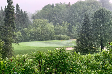 A rain delay on a green golf course and dark cloudy sky on a summer day in Canada