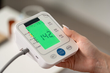 Health Monitoring. Individual checking blood pressure with digital monitor at home.