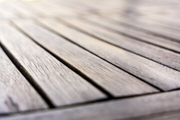 Close-up of wooden garden table planks in diagonal lines with natural sunlight, outdoor surface and...