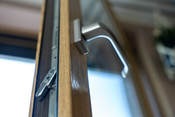 Modern window handle with lock mechanism on wooden frame, interior low angle view of residential...