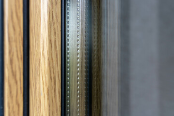Detailed shot of triple glazed window frame with wooden and metal components, showing insulation spacer and layered materials, building technology concept
