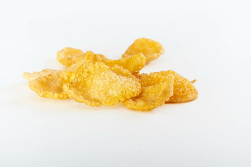 Scattered crunchy cornflakes isolated on white background in macro view for breakfast food themes