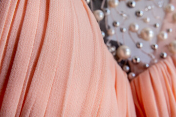 Close-up of soft pleated peach textile with decorative pearls and beaded detail for luxury fashion and design background