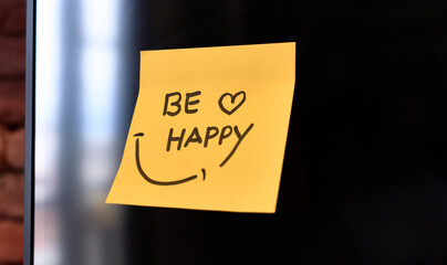 A yellow sticky note with a cheerful message to be happy