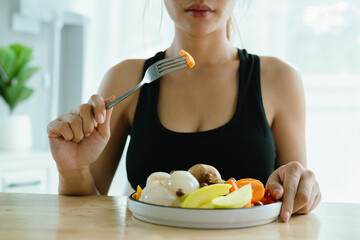 A woman enjoys a fresh, healthy salad made with organic vegetables at home, promoting a balanced lifestyle, fitness, and joy through nutritious eating and mindful preparation.