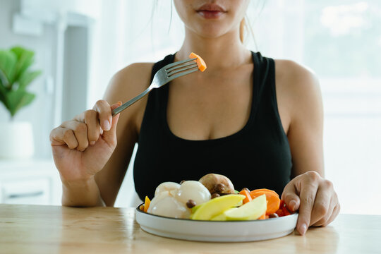 A woman enjoys a fresh, healthy salad made with organic vegetables at home, promoting a balanced lifestyle, fitness, and joy through nutritious eating and mindful preparation.
