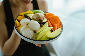 A woman enjoys a fresh, healthy salad made with organic vegetables at home, promoting a balanced...