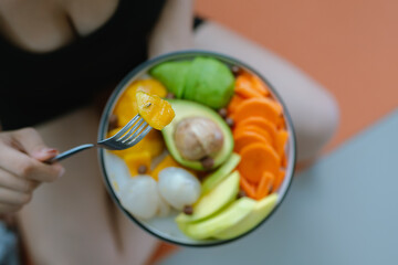 A woman enjoys a fresh, healthy salad made with organic vegetables at home, promoting a balanced...