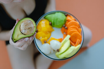A woman enjoys a fresh, healthy salad made with organic vegetables at home, promoting a balanced...