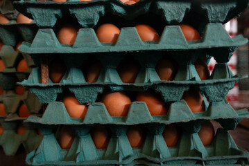 A frame full of chicken eggs in a cardboard box for sale at a market.