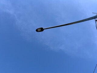 Street lights with a blue sky background with soft clouds, taken from a low angle