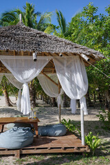 A beautiful beachfront setting in the garden with wooden table, bean bags, white flowing curtains in the private luxury resort in El Nido, Palawan, Philippines. A paradise for summer holidays in Asia
