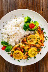Lemon chicken escalopes with rice on wooden table